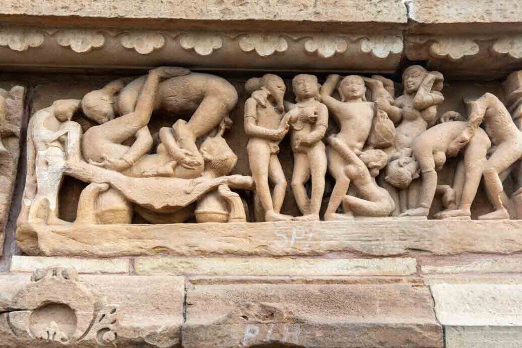 Figure in altorilievo in tutte le posizioni dedite all'amore di gruppo nel tempio di Khajuraho.