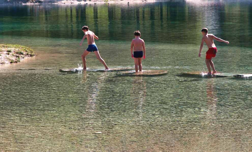 Bambini giocano sul lago di Jasna Ragazzini saltellano sulle pietre affioranti sul lago di Jasna.
