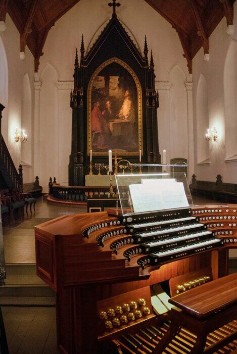 Un organo in legno in primo piano e sullo sfondo l'altare della Cattedrale di Kristiansand.