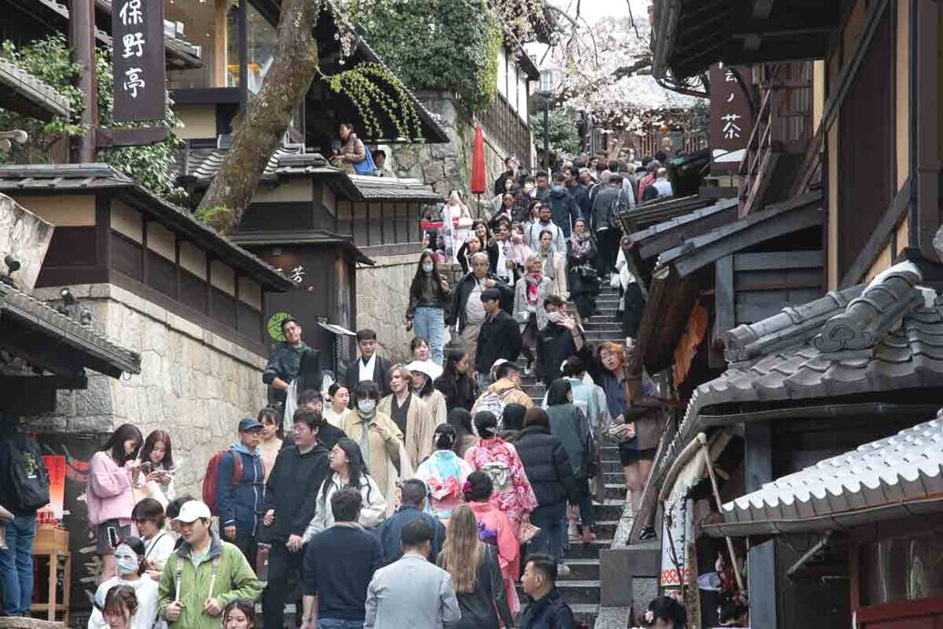 La strada storica di Sannenzaka Tanta gente che passeggia in una strada in salita piena di vecchie strutture in legno adibiti a negozi.