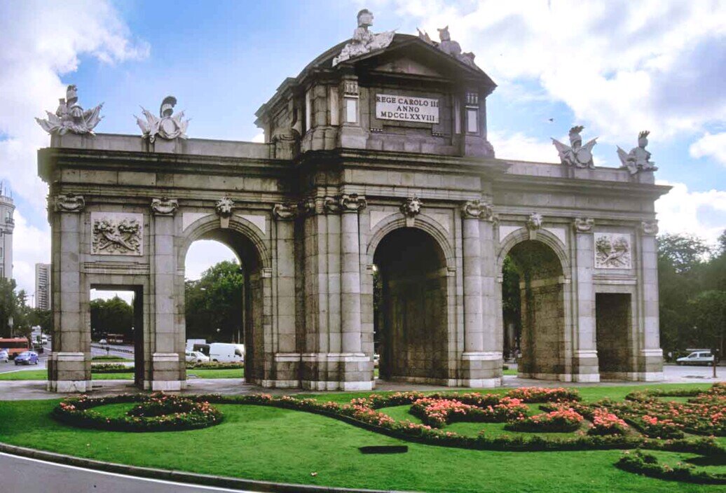 Vista frontale della Puerta de Alcalá, storico arco neoclassico in pietra con cinque arcate, simbolo della città di Madrid.