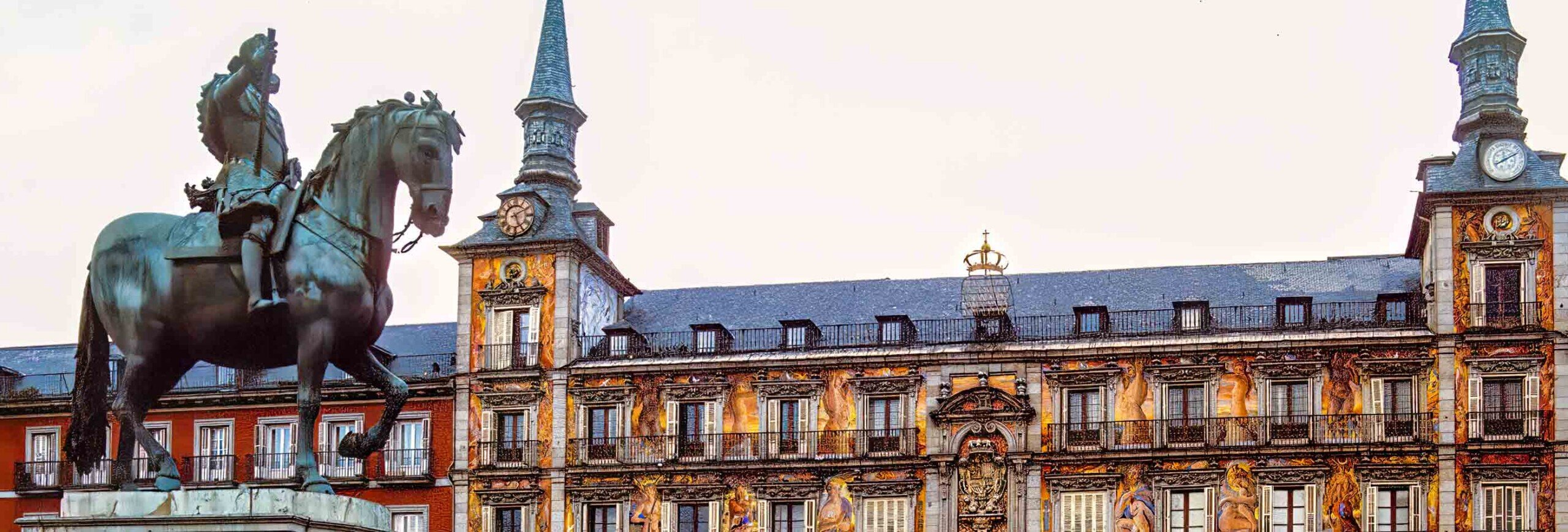 Vista della Puerta del Sol a Madrid con edifici storici decorati con affreschi con in primo piano la statua equestre di Filippo III.