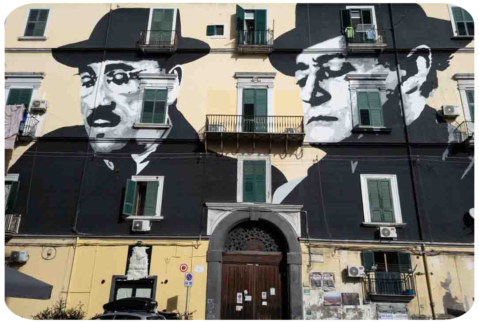Un palazzo con la facciata coperta da un murale con i primi piani di Totò e Peppino de Filippo.