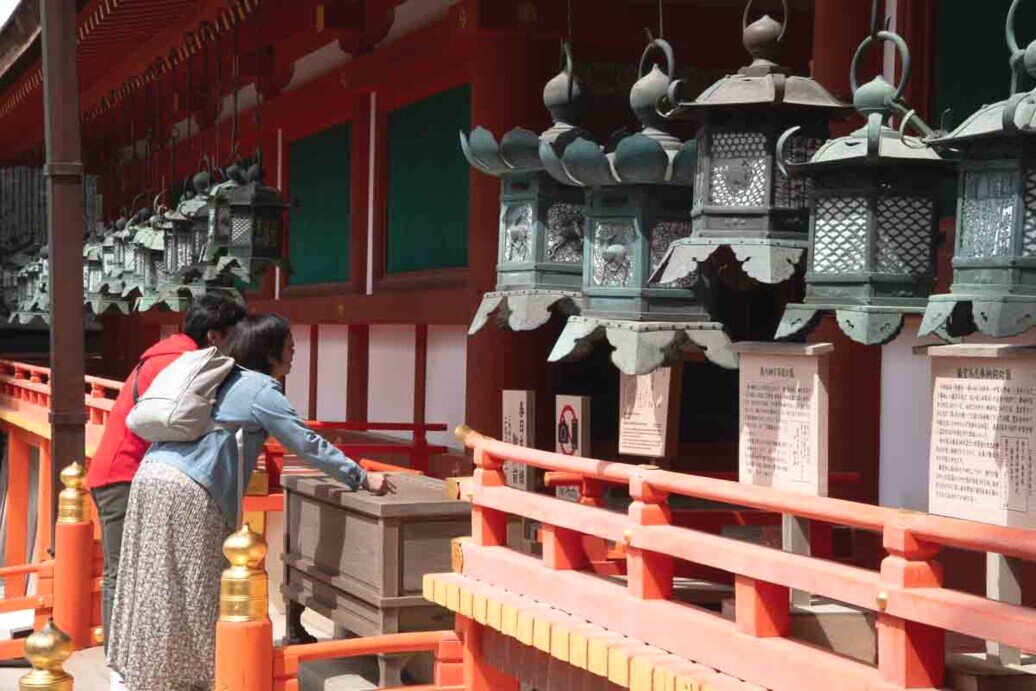Una coppia prega al Tempio Todai-ji davanti a delle lanterne.