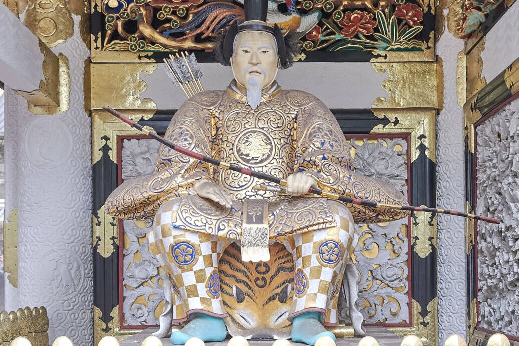 Divinità guardiana seduta con in mano un arco con frecce.