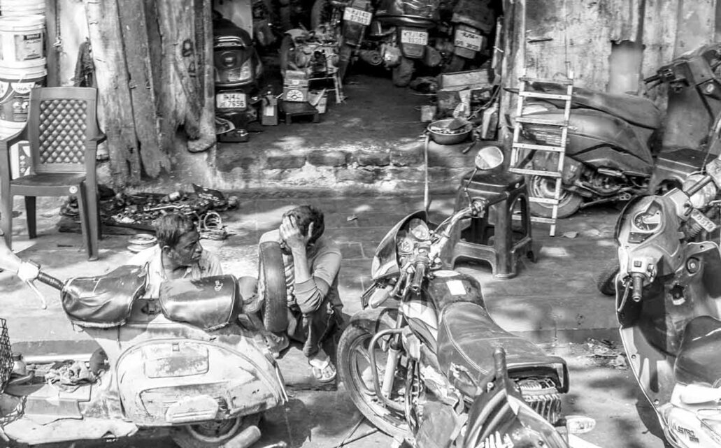 Officina riparazione moto e motocicli con materiali e moto all'esterno come d'uso in India.