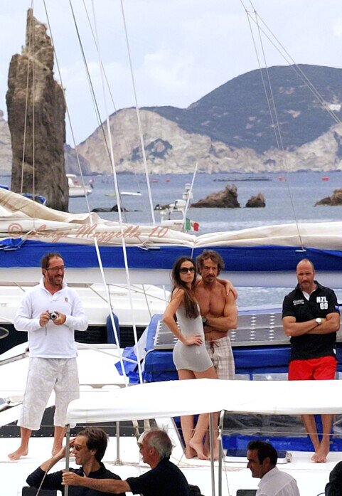Due barche una dietro l'altra con delle persone in attesa davanti ad uno dei faraglioni di Ponza, il giorno di san silverio.