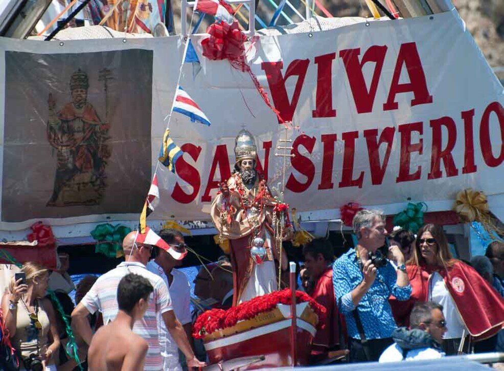 Barca con a bordo la statua San Silverio e dietro un grande striscione dedicato a lui.