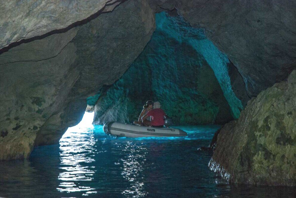 Ponza, interno della grotta di Capo bianco Dentro una buia grotta marina un fascio di luce illumina un piccolo gommone con due persone a bordo.
