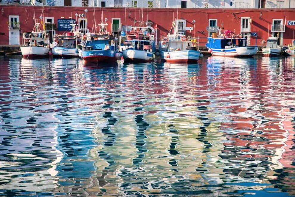 Il mare appena increspato riflette i colori delle imbarcazioni ancorate al porto di Ponza.