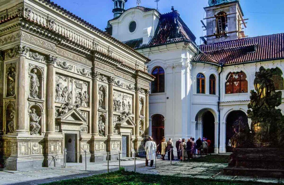 Facciata della Santa Casa nel complesso della Chiesa di Loreto a Praga, con decorazioni rinascimentali e visitatori nel cortile.