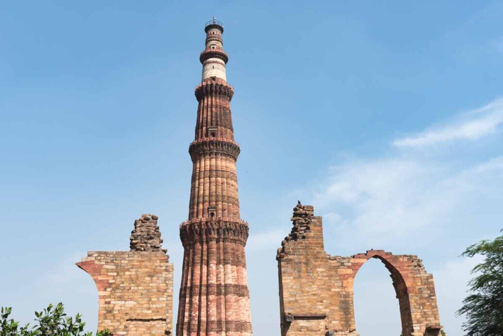 Un'alta torre di pietra è il minareto della moschea di Qutub Minar. 