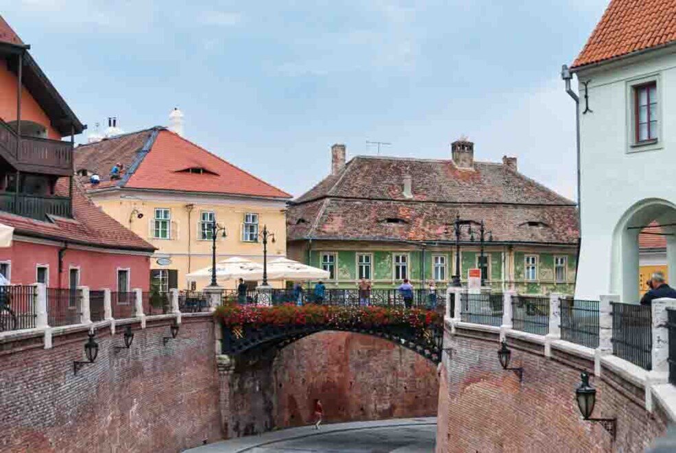 Il ponte di Sibiu Un ponte che sovrasta una strada con case colorate sullo sfondo.