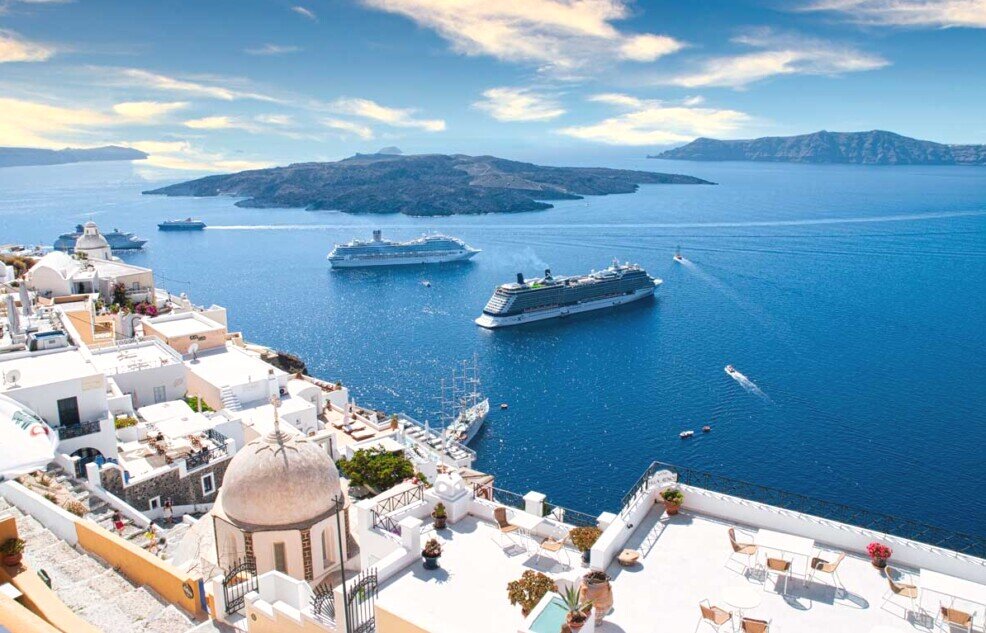 Panorama dal villaggio di Firà con le sue piazzette sul bordo dello strapiombo, in mare una nave da crociera ancorata, e sullo sfondo l'isolotto di Nea Kameni, punta di un vulcano ancora attivo.