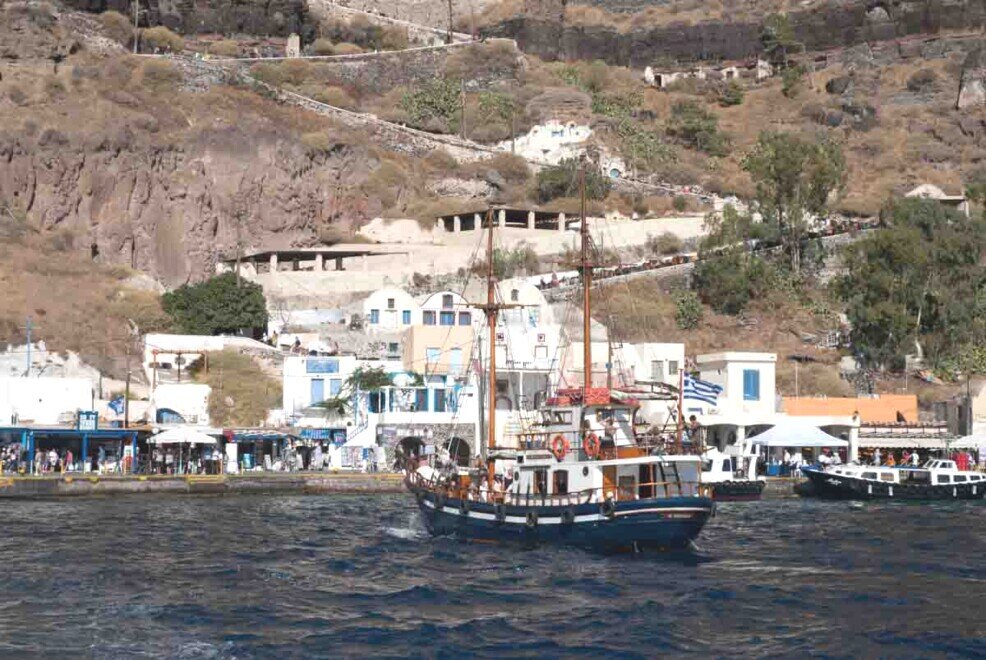 Una imbarcazione che trasporta turisti sta per approdare al vecchio porto di Firà.