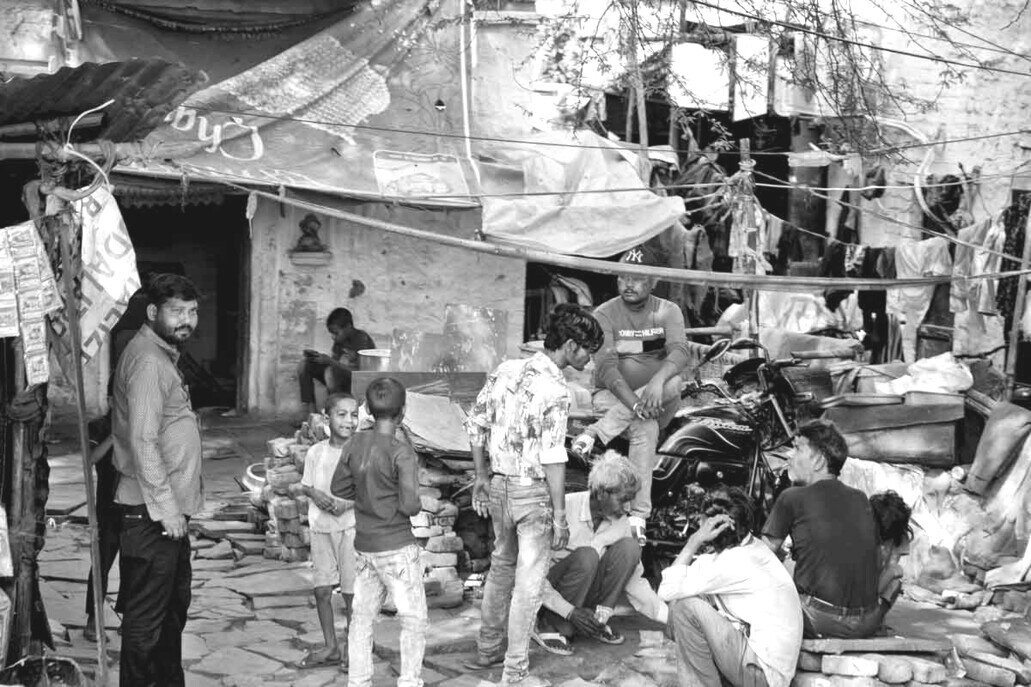 Scena di vita quotidiana in un quartiere popolare di Jaipur, India, con abitanti, bambini e case tradizionali.