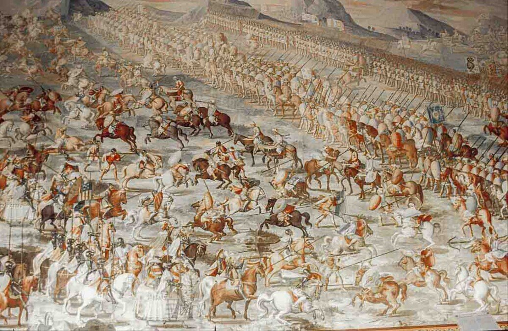 Affresco che rappresenta scene di battaglie storiche vinte dagli eserciti spagnoli — tra cui la Battaglia di La Higueruela e quella di San Quintín — con figure di soldati, cavalli e paesaggi di guerra tipici del XVI secolo.