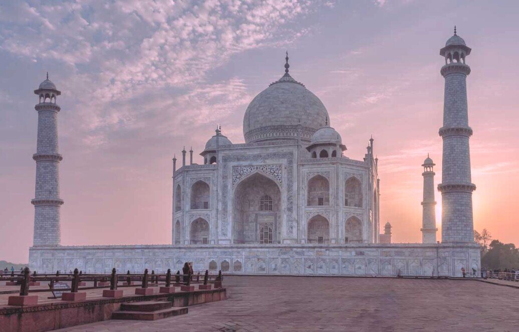 Il taj mahal si staglia davanti al sole dell'alba con i suoi minareti.
