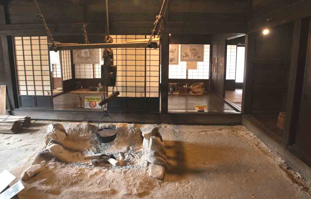 Hida Folk Village sala con focolare Grande sala con focolare sul pavimento in terriccio e salone a fianco con pavimento in legno separati da una parete scorrevole.