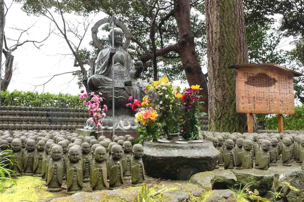 Statua di Buddha al centro, circondata da molte statue di jizo, all'interno del Tempio di Hase-dera, luogo di meditazione.