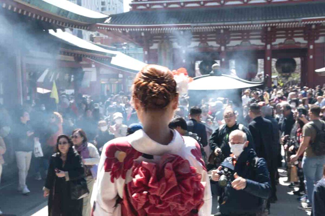 tempio buddista di Sensō-ji Ragazza in Kimono che guarda la piazza affollata del tempio buddista di Sensō-ji.
